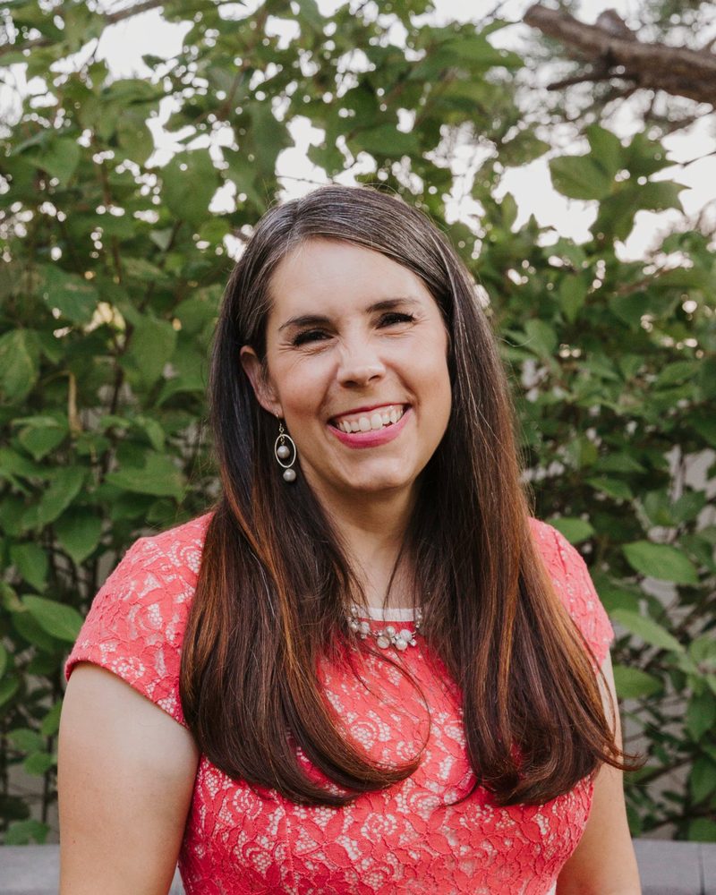 Jessica Haviland smiling outdoors in a coral dress